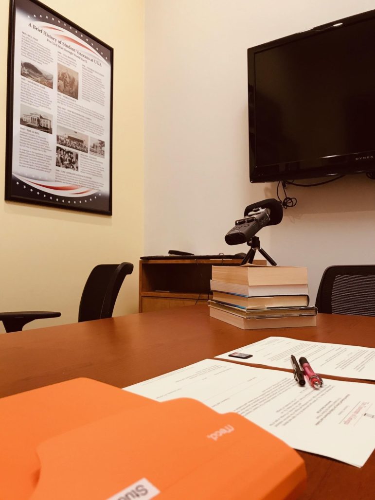 A voice recorder on a stack of books on a conference table