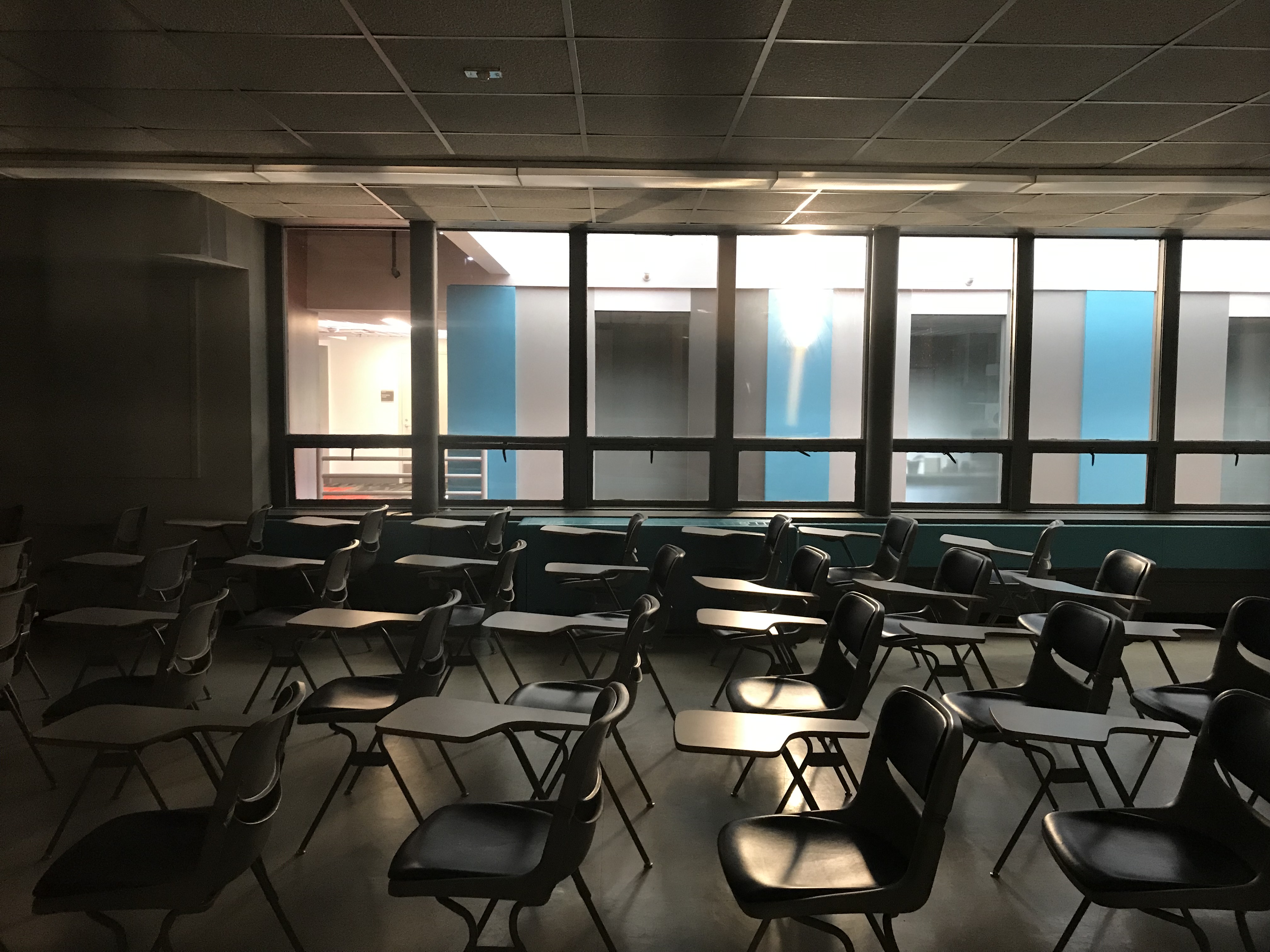 An unlit empty classroom filled with desks.
