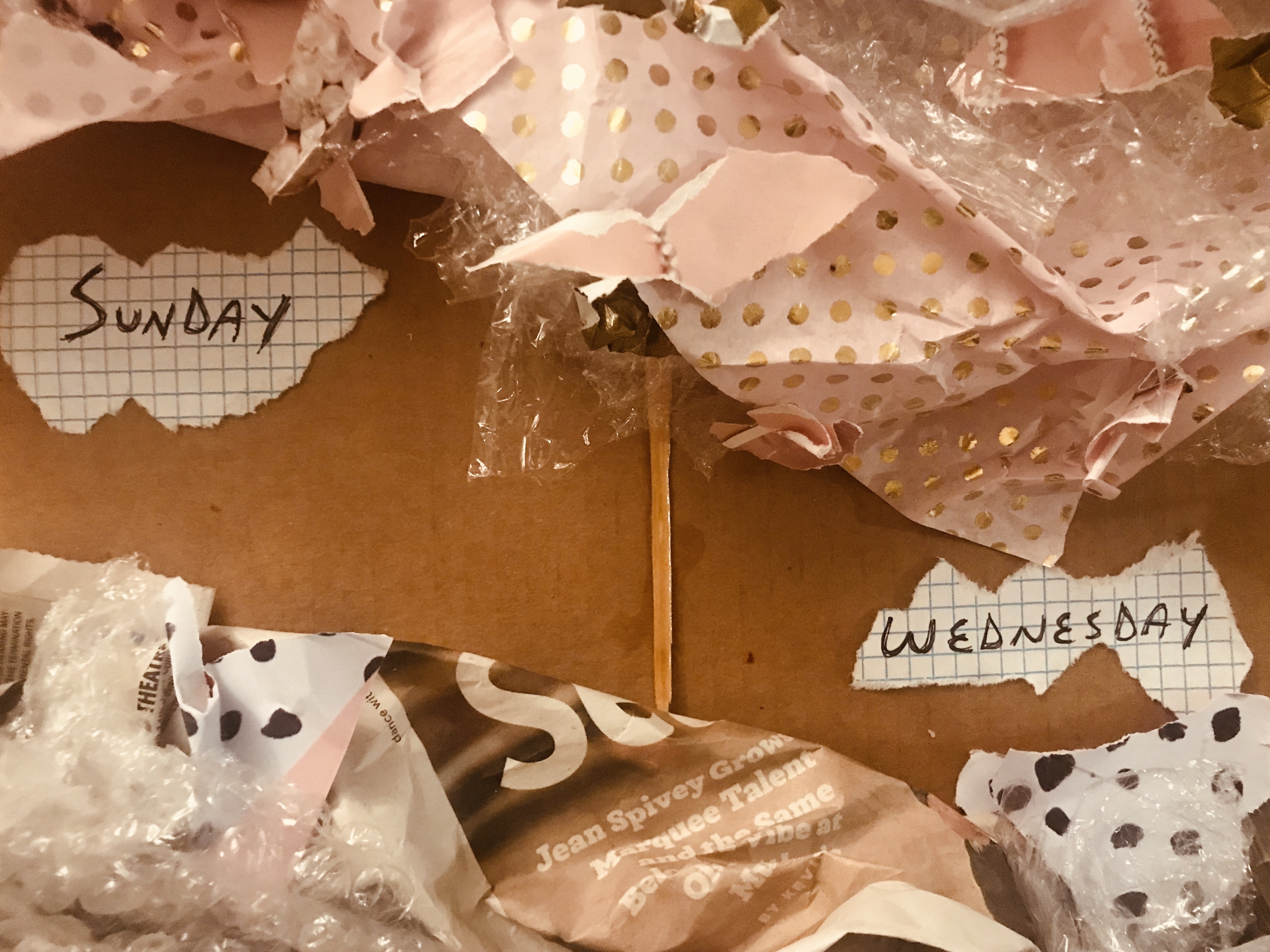 What follows is a series of images wherein a poem is presented handwritten on scraps of graphic paper, against a background of crumpled up newspaper, bubble wrap, and wrapping paper. In the first image, we see the title: Sunday / Wednesday.