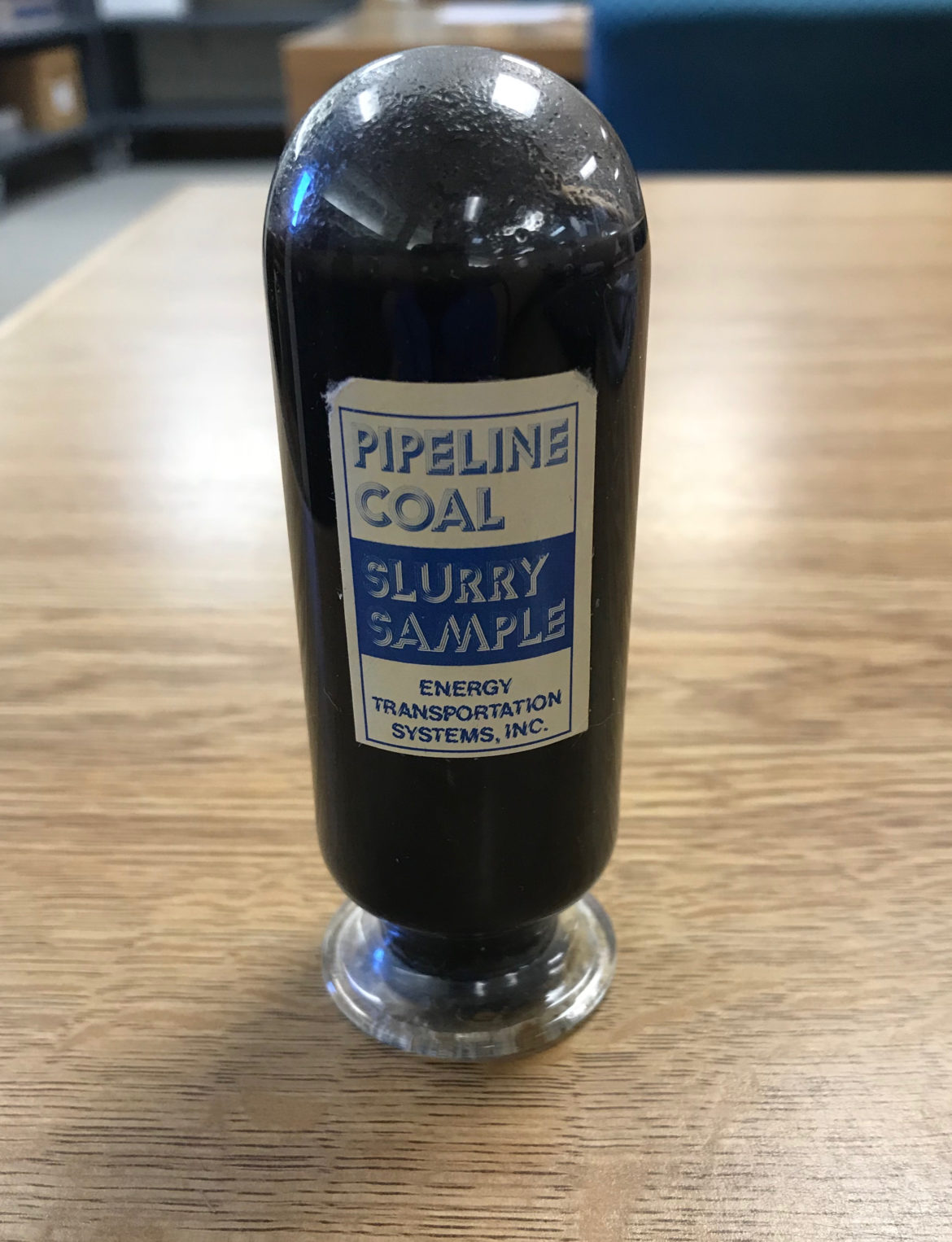 The bottle of coal slurry. The label reads, "Pipeline coal slurry sample, Energy Transportation Systems, Inc."